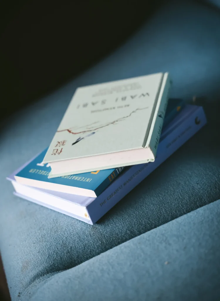 A stack of three books resting on a blue sofa.